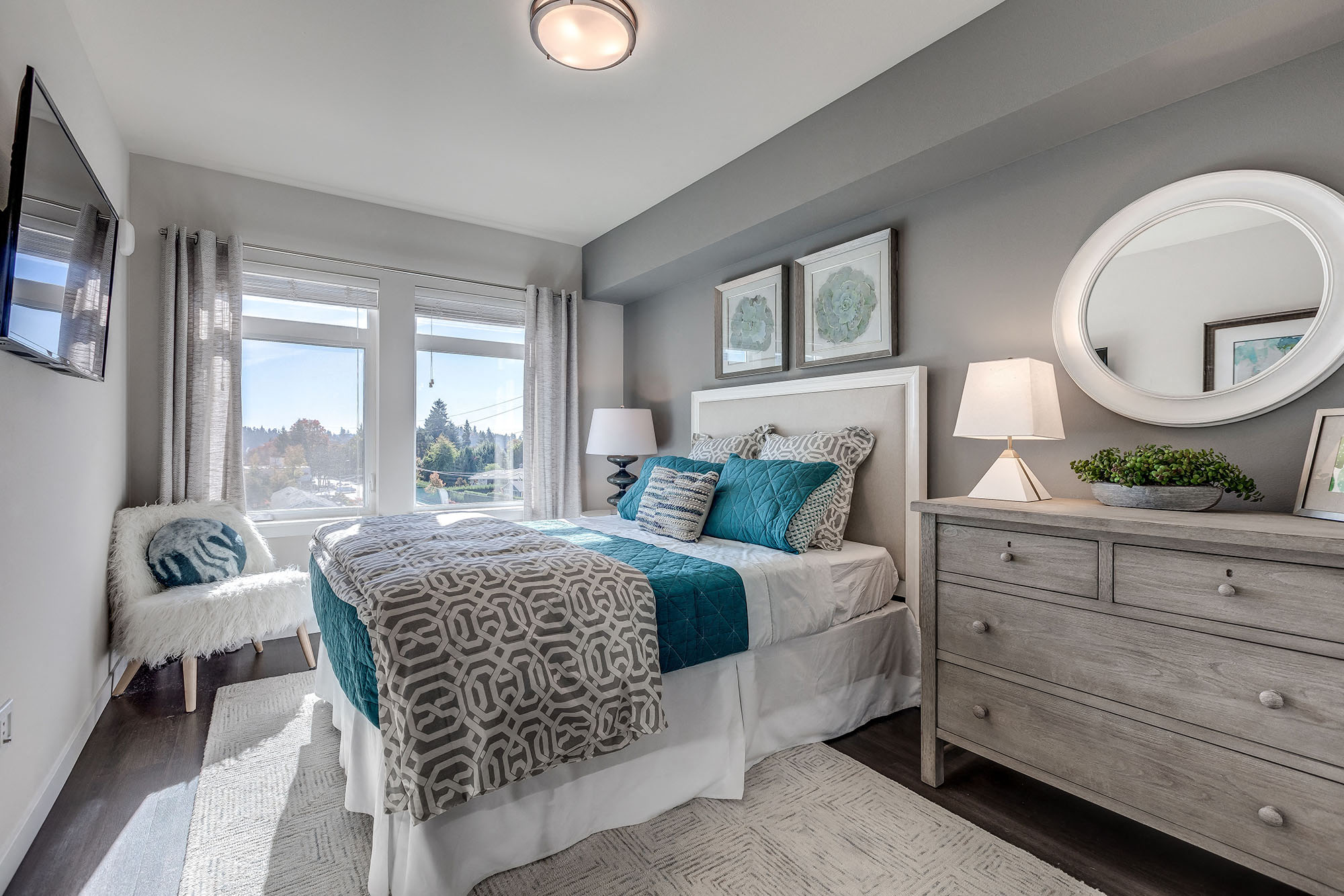 Lux Apartments Bellevue spacious bedroom with large windows, a queen-sized bed, side table and dresser with extra room to walk around the bed